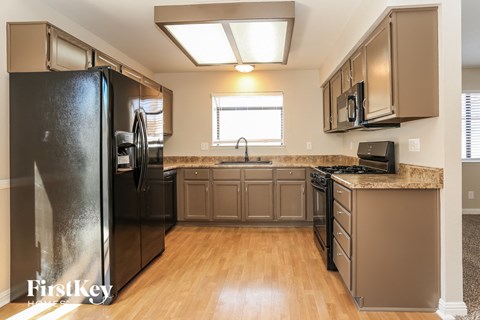 A kitchen with a black fridge and wooden floors.