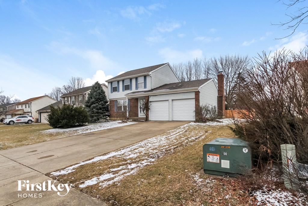 A house with a driveway and a green utility box in front.