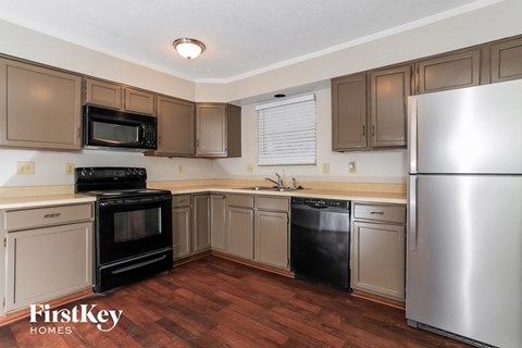 A kitchen with a refrigerator, oven, and microwave.