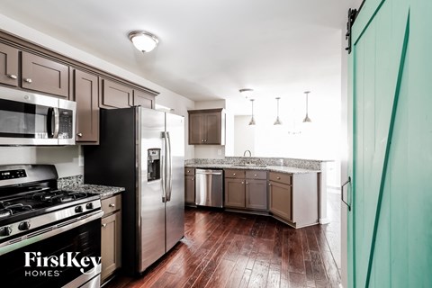 A kitchen with a stove top oven, microwave, refrigerator, and sink.