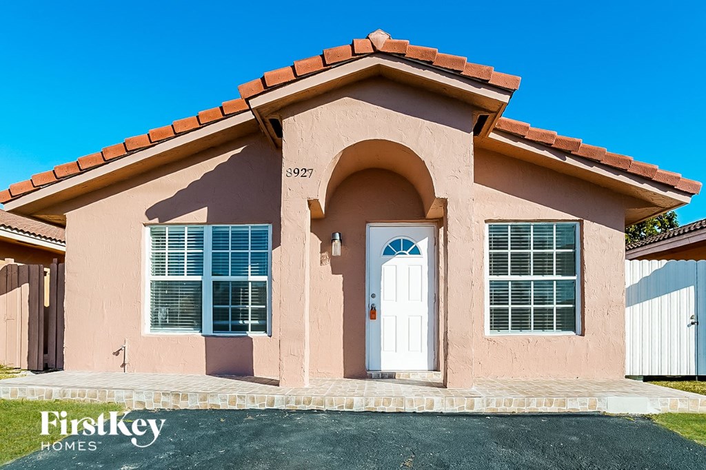 a pink house with a white door and a blue sky