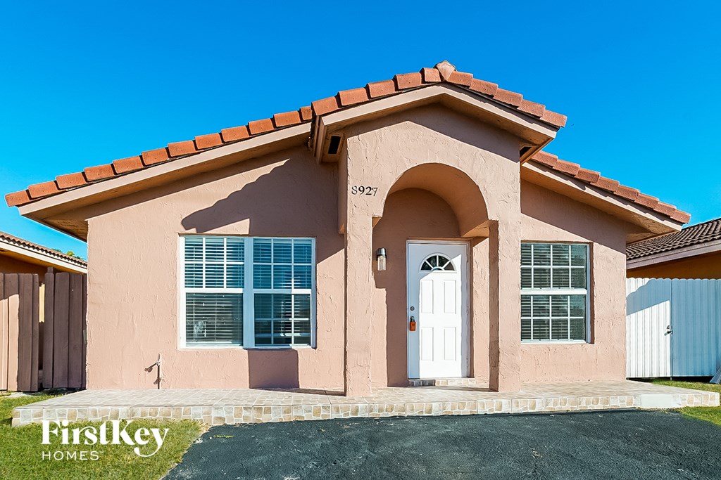 a pink house with a white door and a blue sky