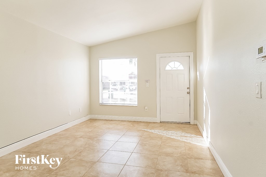 an empty living room with a white door and tiled floors