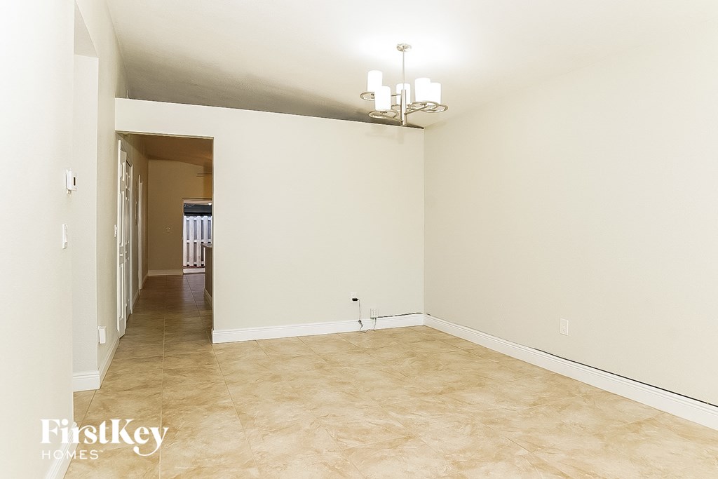 a empty living room with a hallway to the dining room