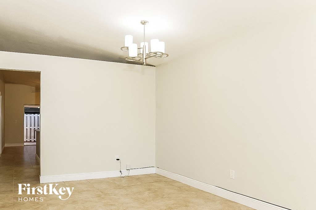 a empty living room with a chandelier and white walls