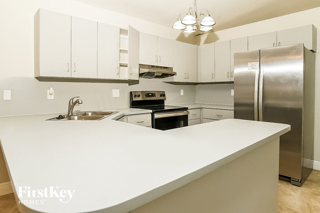 a white kitchen with stainless steel appliances and white countertops