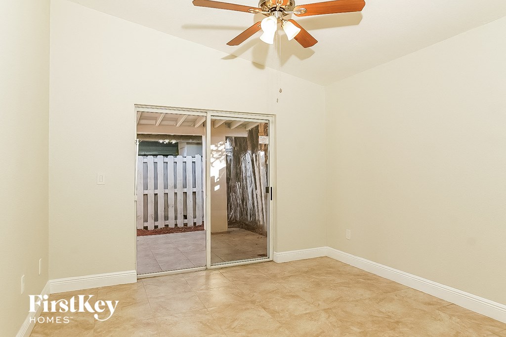 the living room of a home with a ceiling fan and a door to a hallway