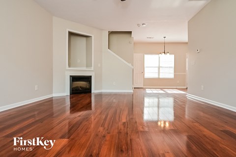 A spacious room with wooden floors and a fireplace.