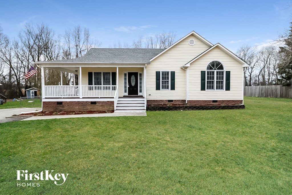 the front view of a white house with a porch and a lawn