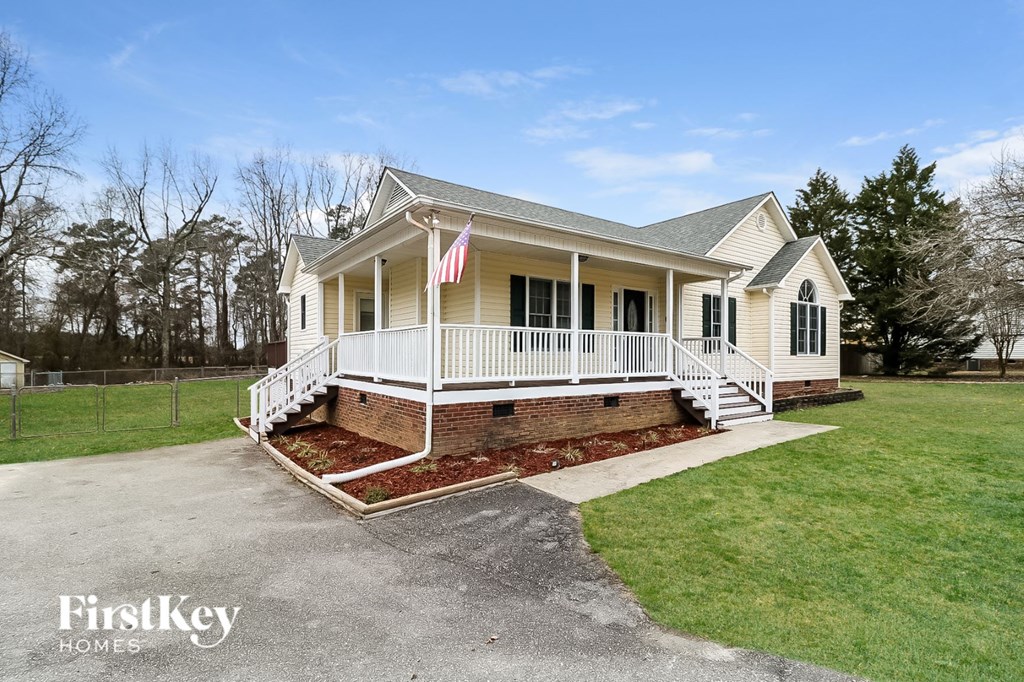 the front exterior of a yellow house with a white porch and an flag