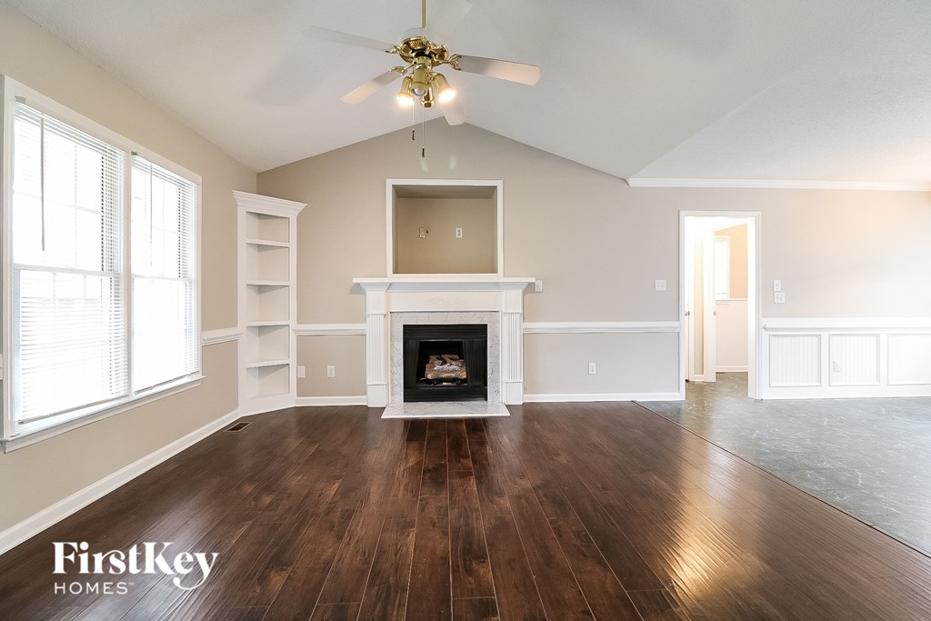 an empty living room with a fireplace and a ceiling fan