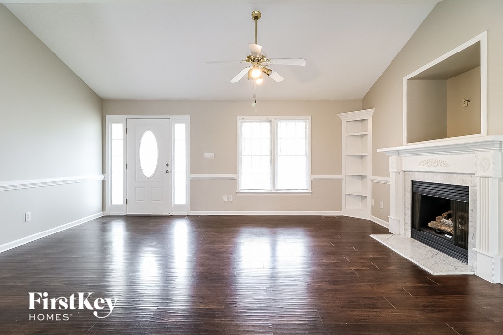 an empty living room with a fireplace and a ceiling fan