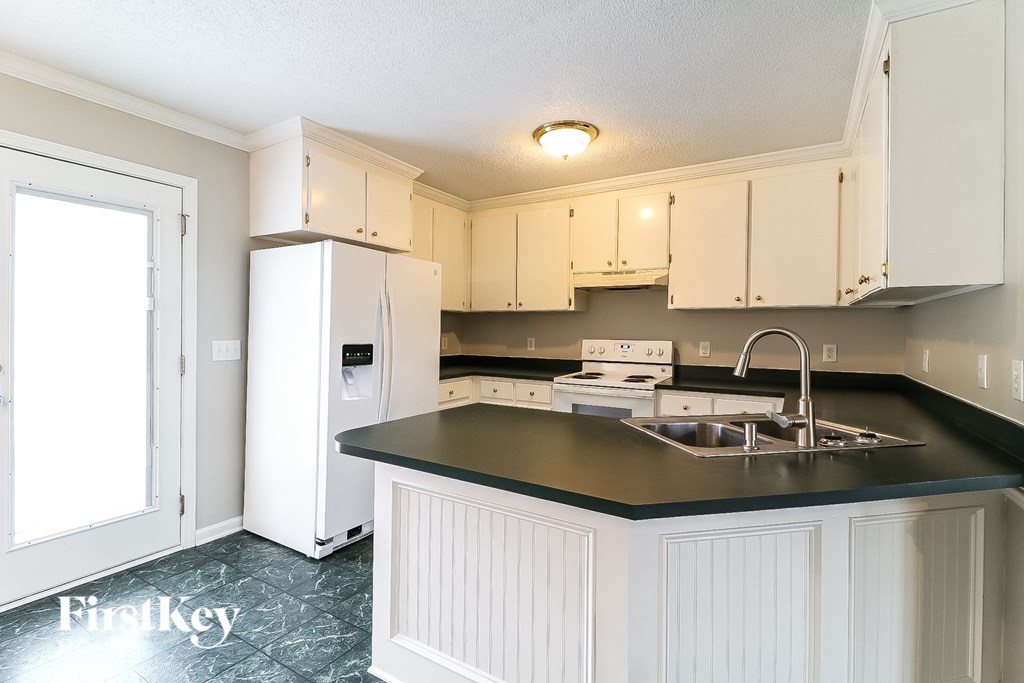a kitchen with white cabinets and a black counter top