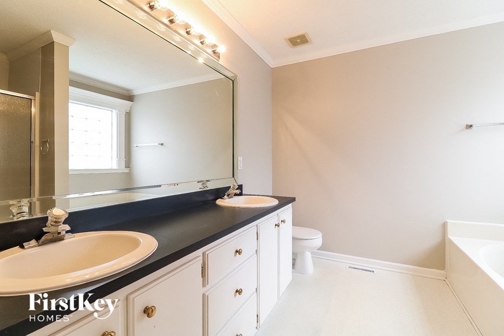 a bathroom with two sinks and a mirror and a toilet
