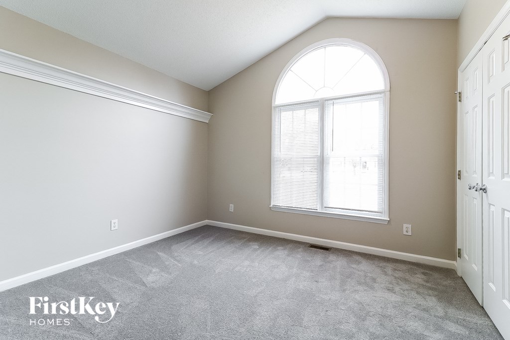 an empty bedroom with a large window and white doors