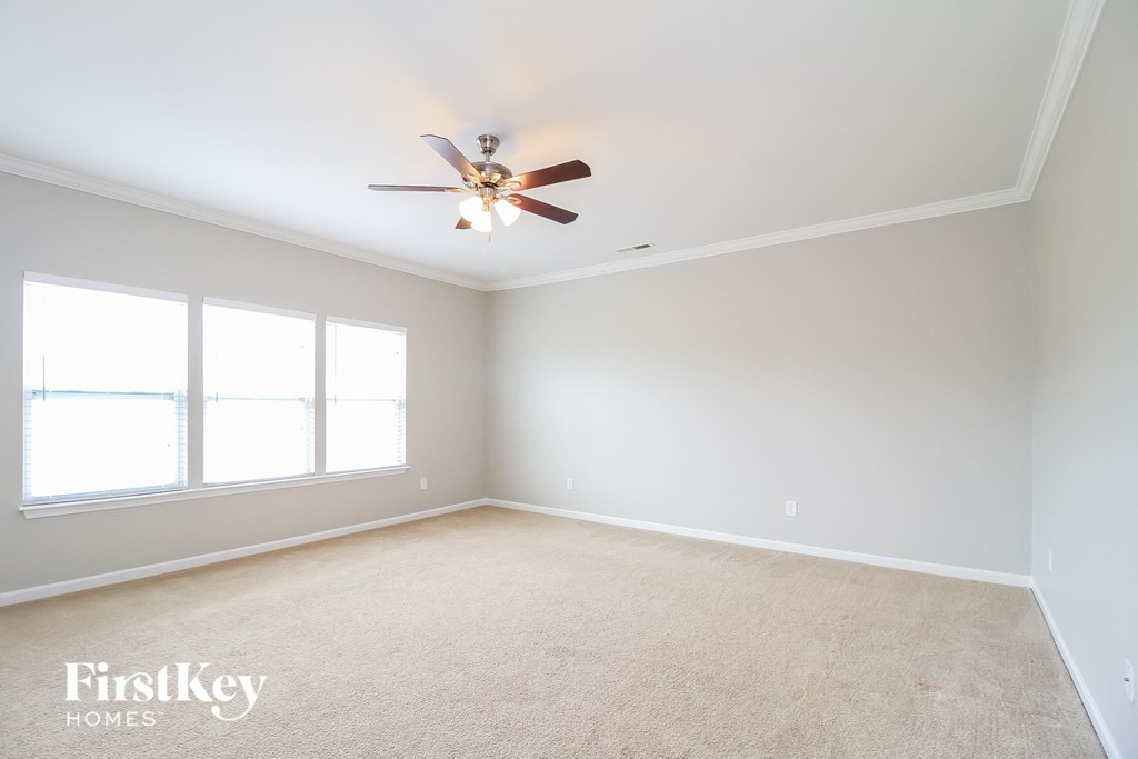 A room with a ceiling fan and carpeted floor.