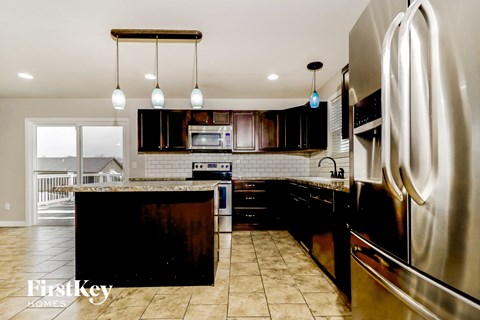 A modern kitchen with a stainless steel refrigerator and a black island.