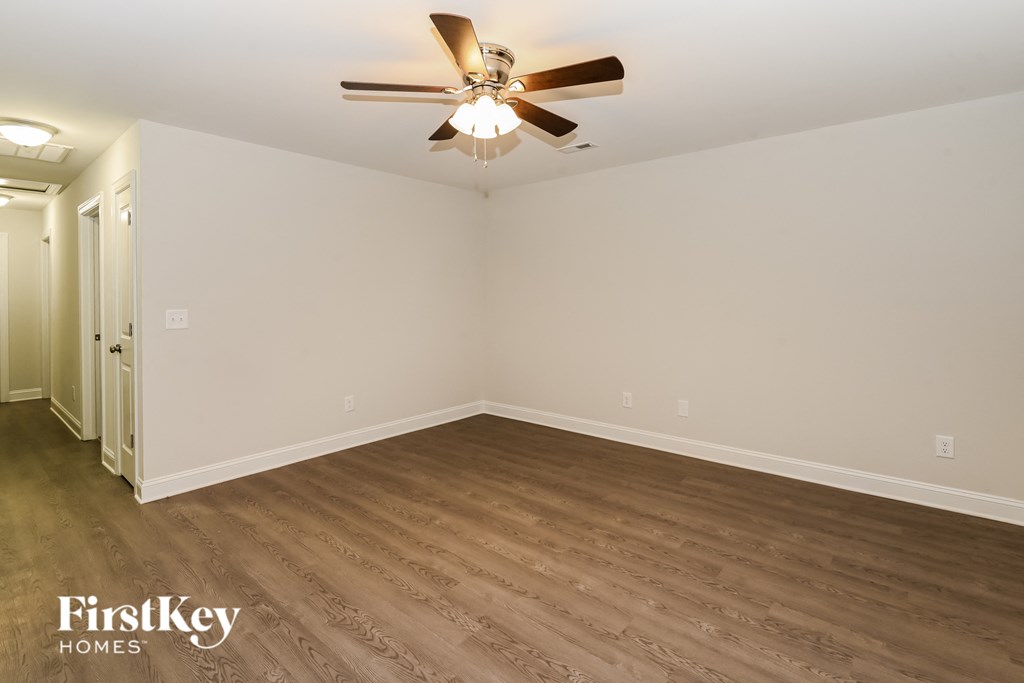 the living room of an empty house with wood flooring and a ceiling fan