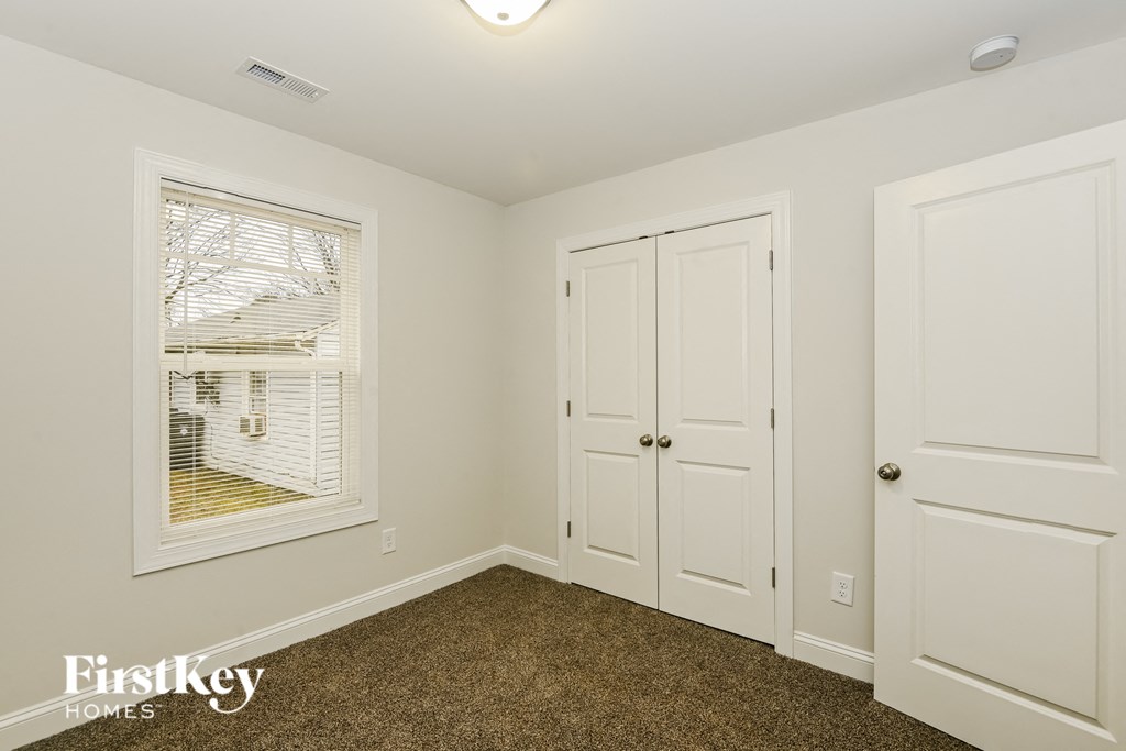 a bedroom with two closets and a window and a carpeted floor