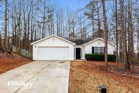 a white house in the woods with a driveway