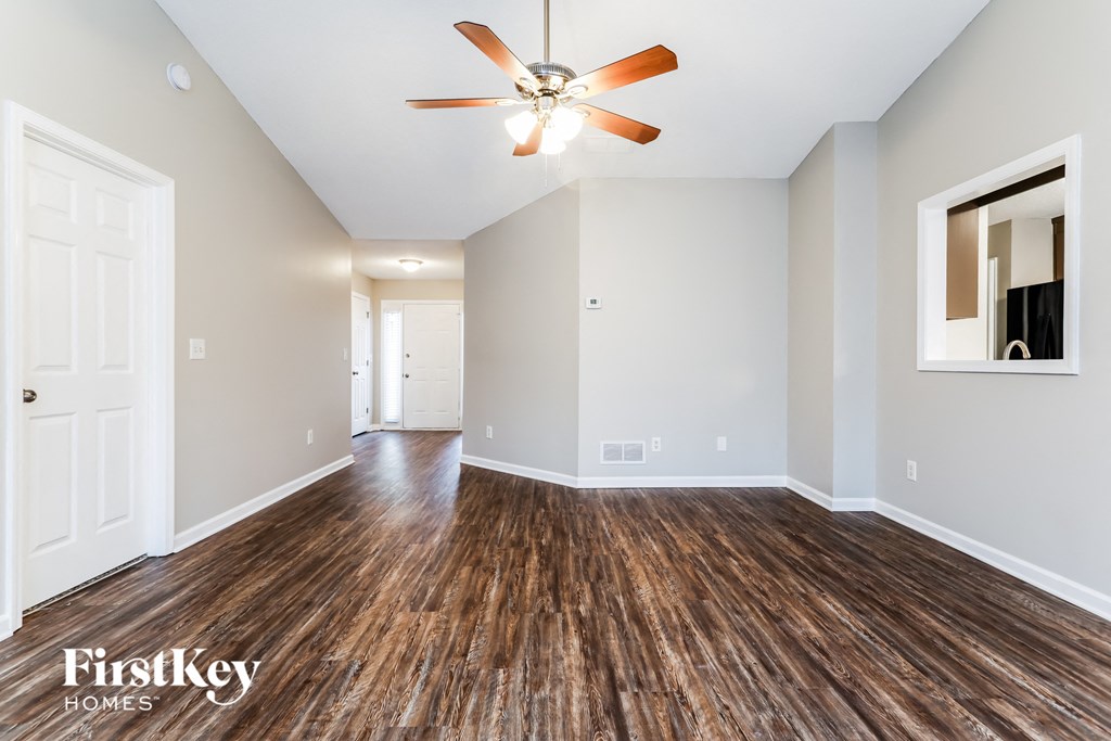 an empty living room with wood flooring and a ceiling fan