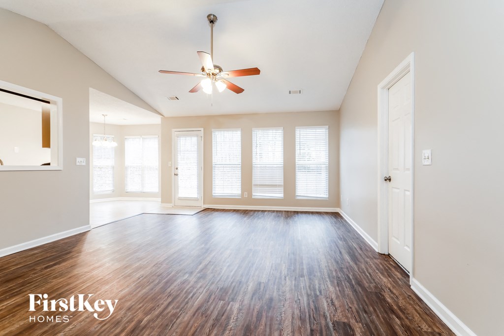 an empty living room with wood floors and a ceiling fan