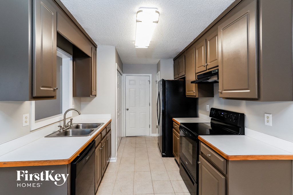 a kitchen with black appliances and white counters and wooden cabinets