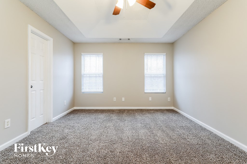 an empty room with carpet and two windows