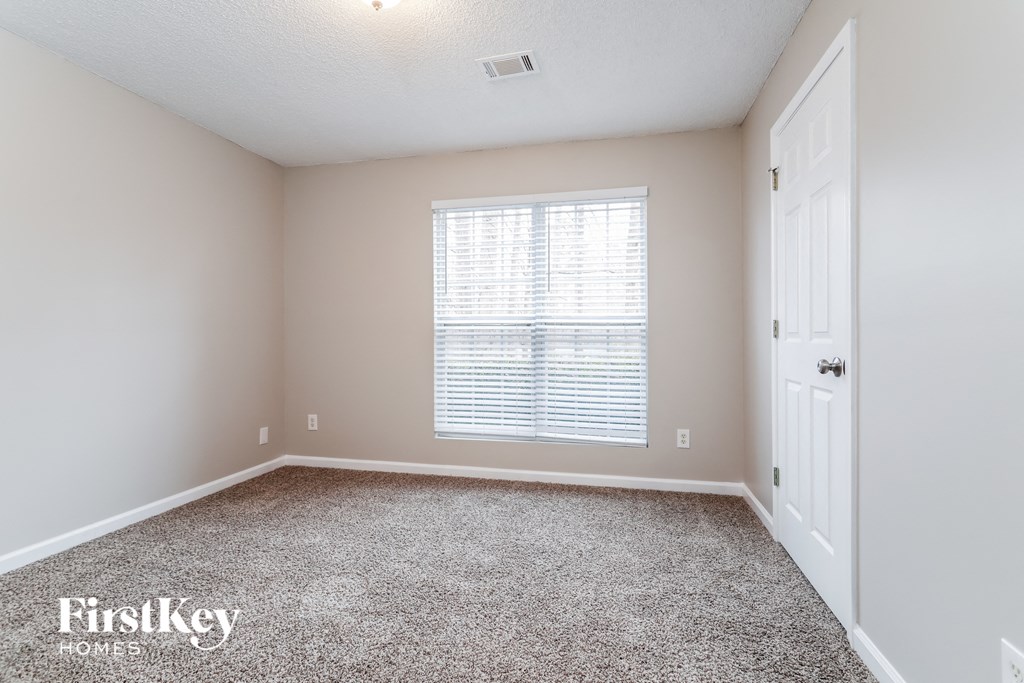 a bedroom with carpet and a window and a white door