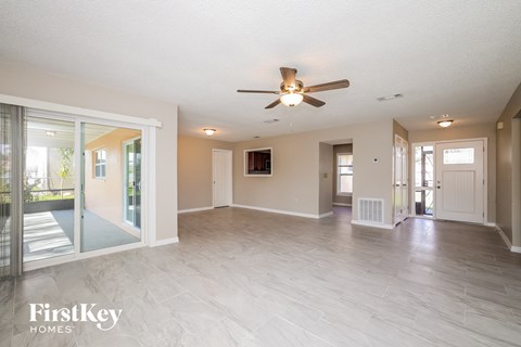 an empty living room with a ceiling fan and sliding glass doors