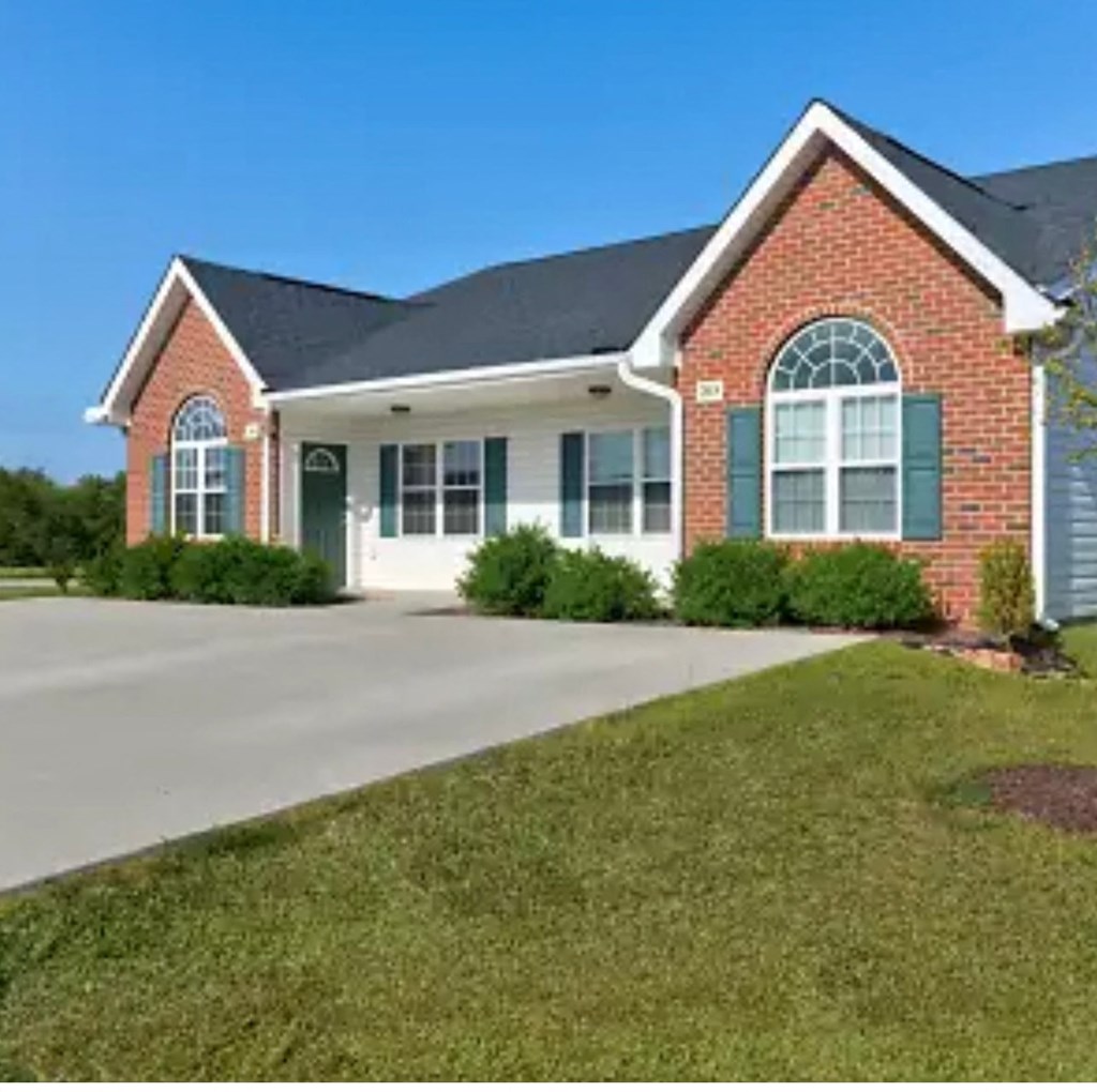 A red brick house with green shutters and a white garage door.