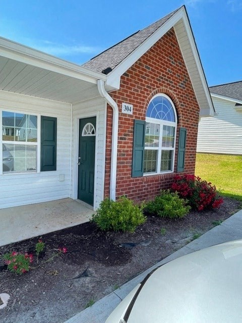 A house with a green door and a window with green shutters.