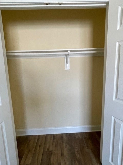 A white door is open to a room with a white baseboard and a white shelf.