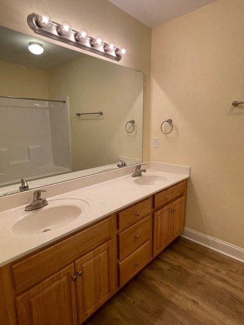 A bathroom with two sinks and a mirror with lights above it.
