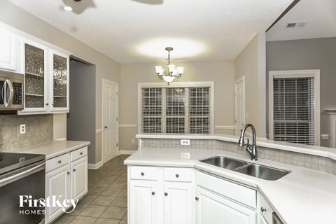 A kitchen with white cabinets and a stainless steel sink.