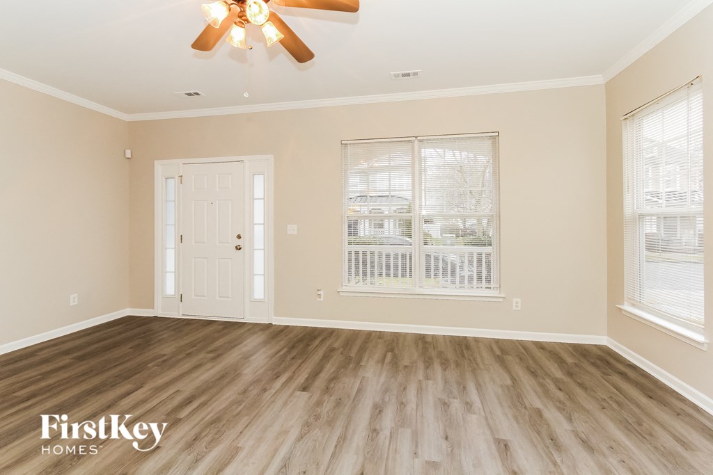 the living room of a home with wood floors and a ceiling fan