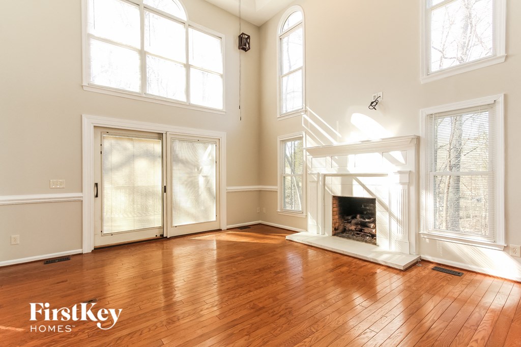 A large, empty room with wooden floors and a fireplace.