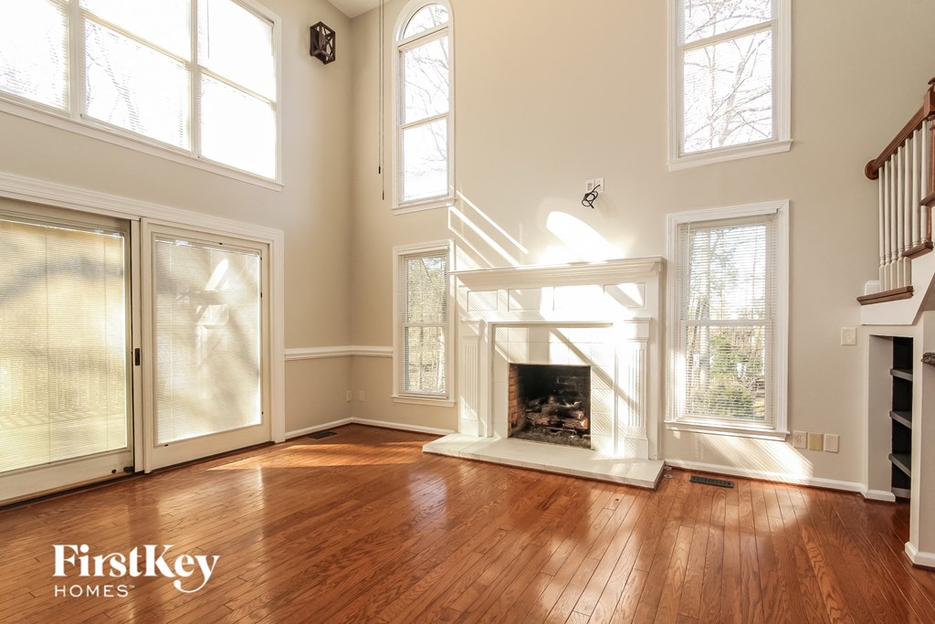 A large, empty room with wood floors and a fireplace.