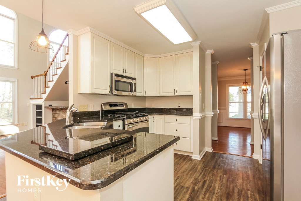 A kitchen with a black granite counter top and white cabinets.