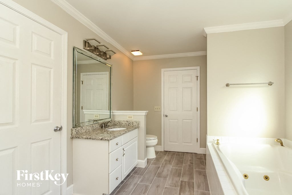A bathroom with a tub, sink, mirror, and toilet.