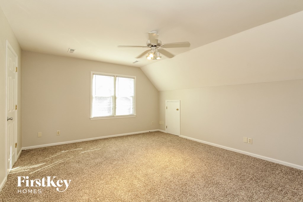 A spacious room with a ceiling fan and a window.