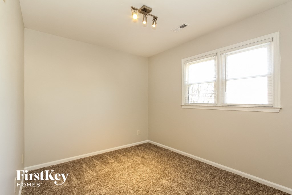 A room with a window and a carpeted floor.
