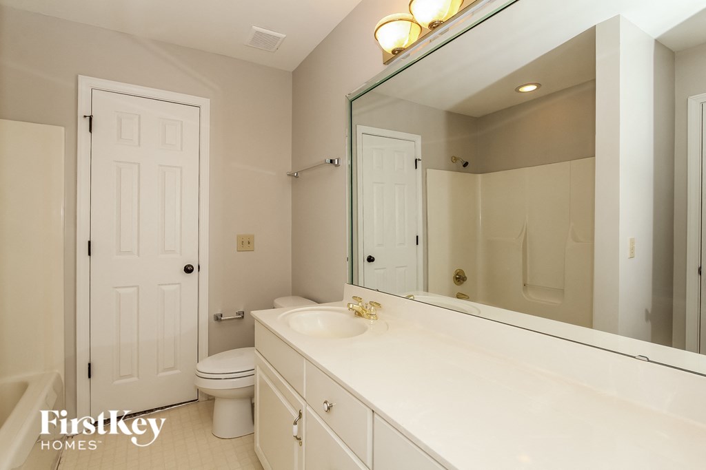 A white bathroom with a mirror and a toilet.
