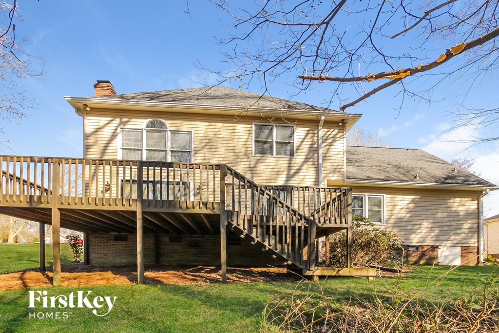 A house with a wooden deck and stairs leading to the basement.