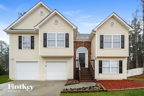 A two-story house with a garage on the first floor and a staircase leading to a door on the second floor.