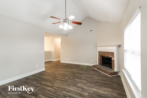 A spacious room with a fireplace and a ceiling fan.