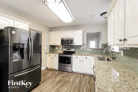 A kitchen with a black fridge and wooden floors.