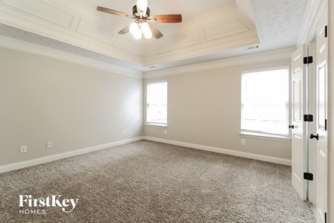 A room with a carpeted floor and a ceiling fan.