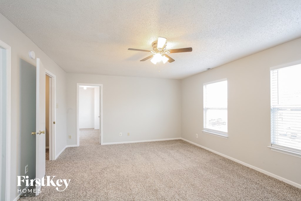 a spacious living room with carpet and a ceiling fan