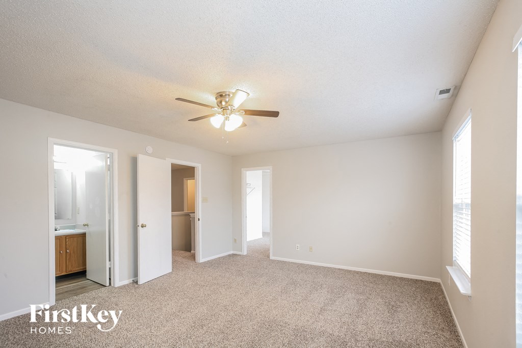a spacious living room with carpet and a ceiling fan